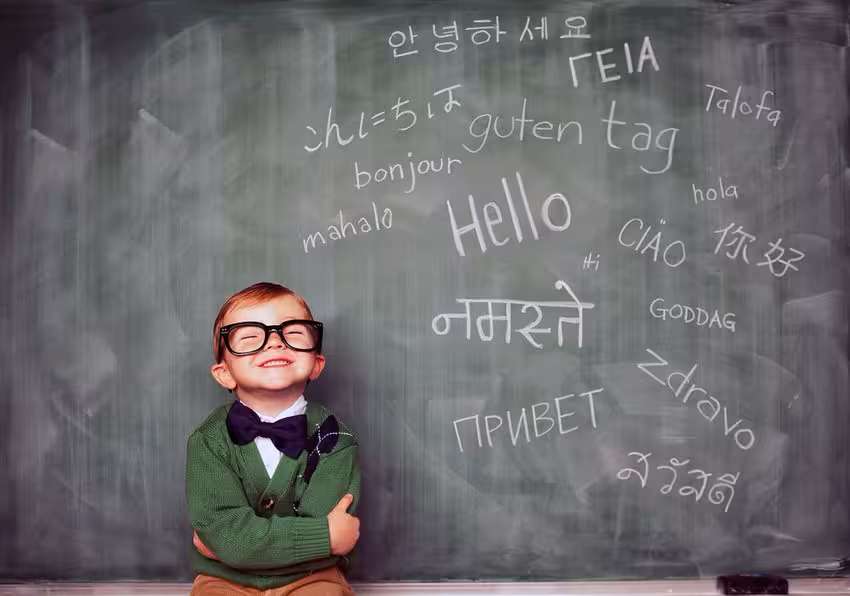 Keep-your-brain-healthy-–-the-added-benefits-of-being-bilingual-a-kid-smiling-next-to-a-blackboard-Montessori-Method