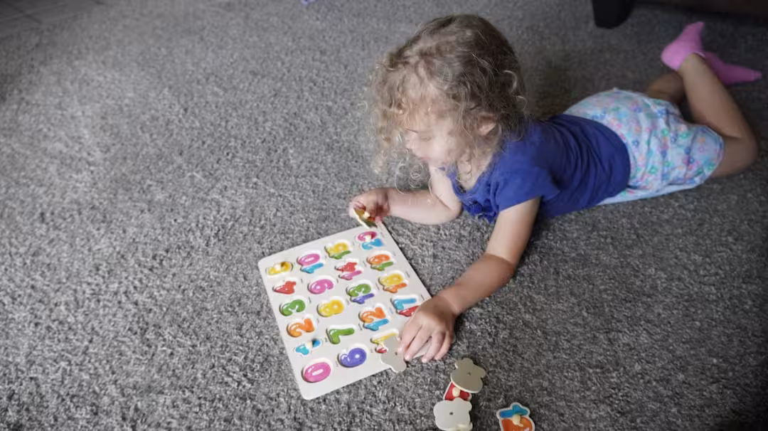 Toddler playing with alphabet puzzle on carpet