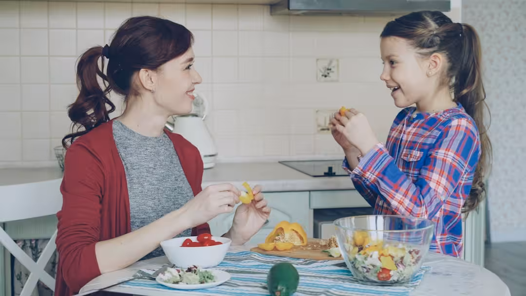 Mother and daughter prepare fruit salad together.