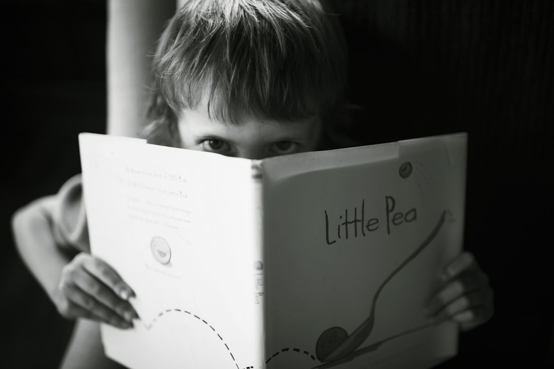 cuándo empezar a leer con niños - Niño pequeño pasando páginas de un libro de cartón, exploración sensorial típica de 12-18 meses.