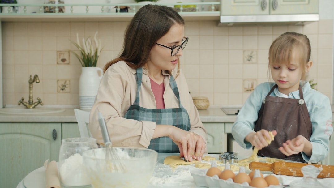 juegos que aumentan el foco en niños - Niño cocinando con un adulto en la cocina, midiendo ingredientes con atención