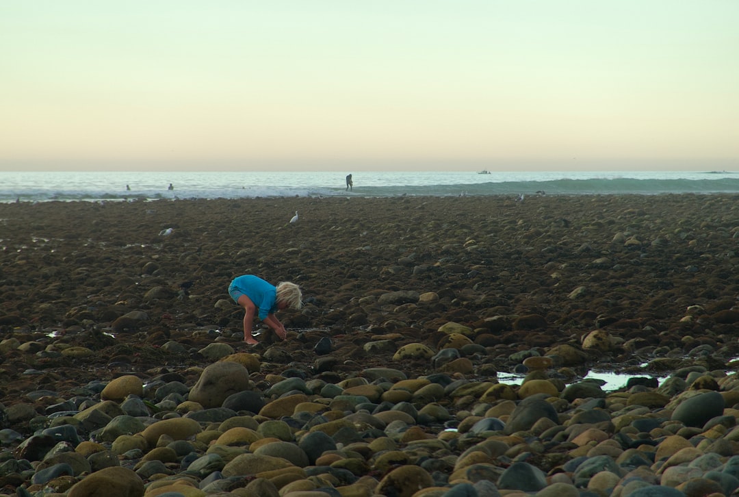 experiencias sensoriales Montessori - Niño recogiendo piedras en la playa para clasificar