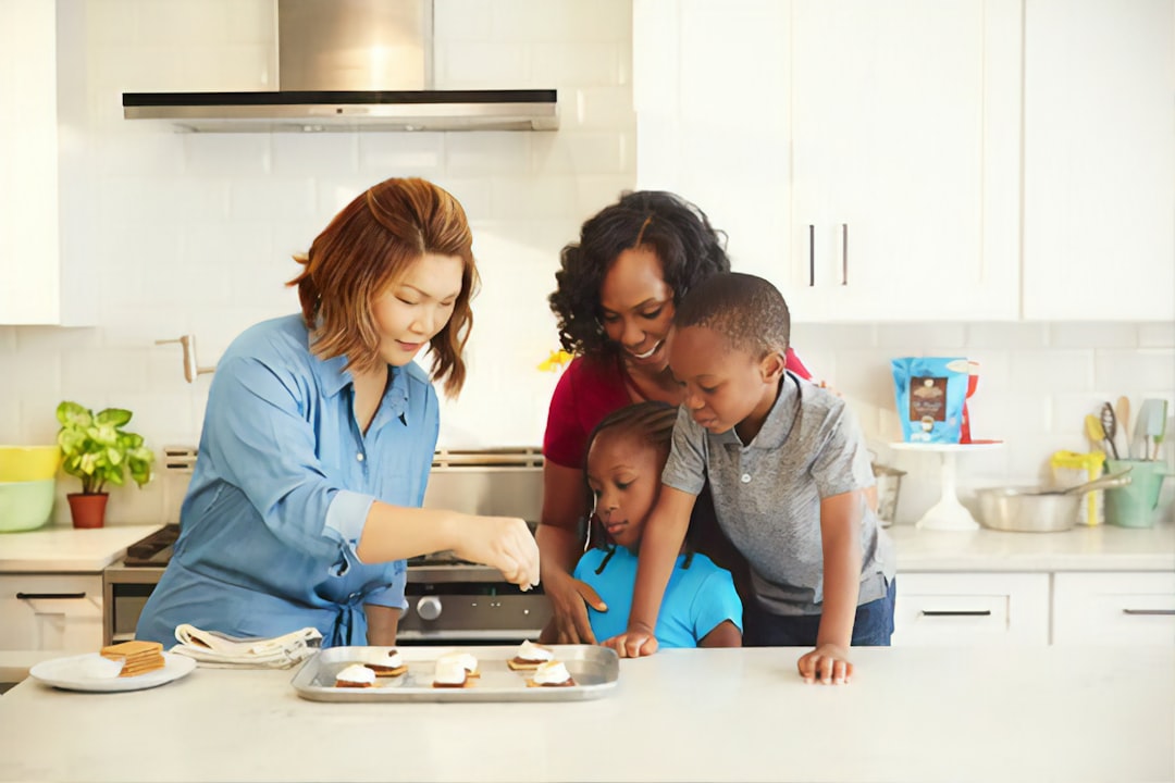 pedagogía Montessori en casa - Familia cocinando junta con un niño pequeño sobre torre de aprendizaje