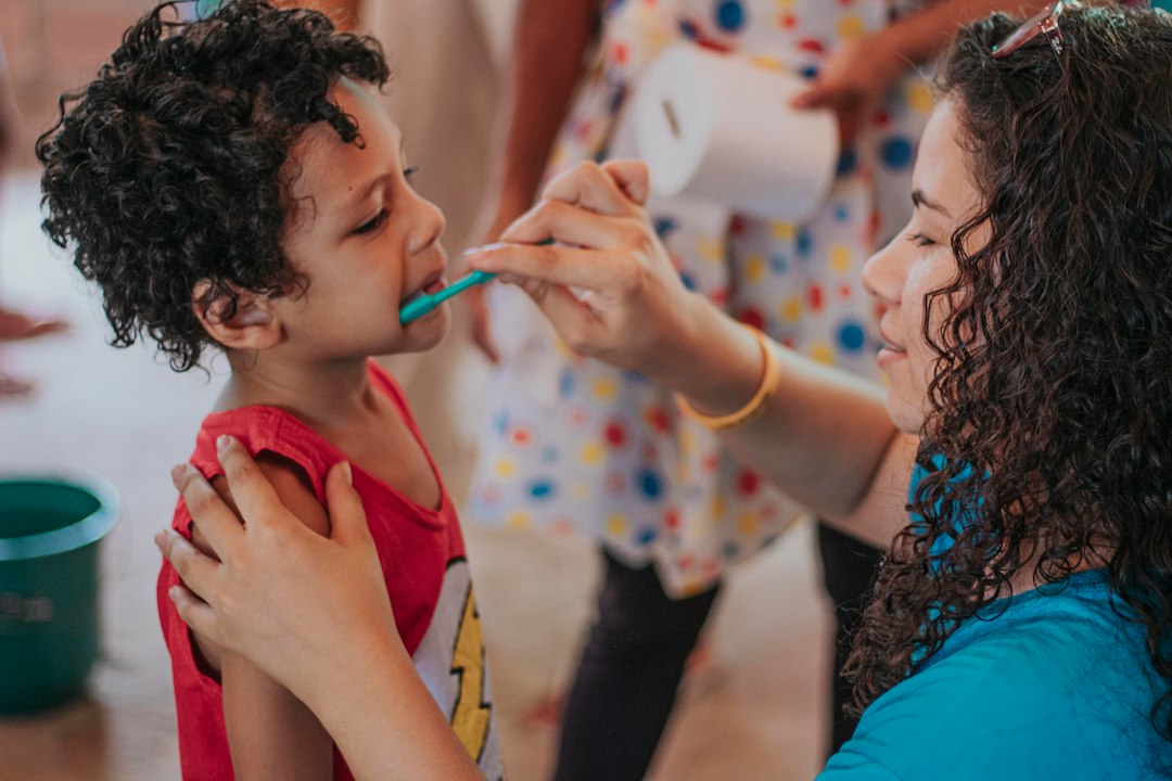 cuidado dental infantil - El niño participa, mientras la persona adulta completa el cepillado.