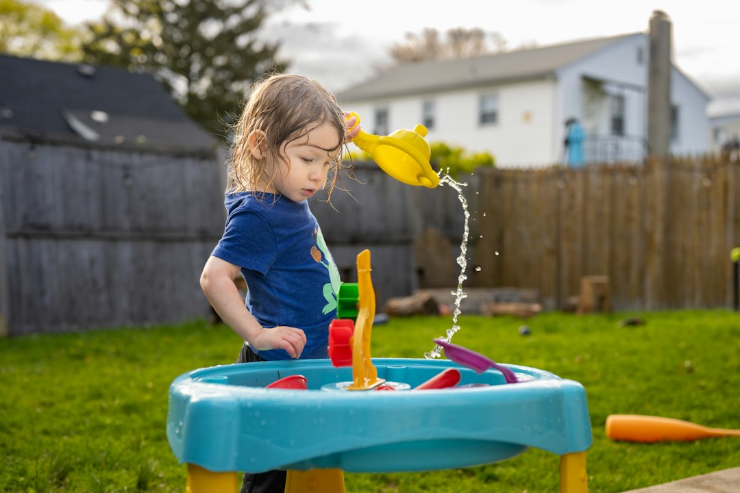 juegos sensoriales para bebés - Un niño pequeño practica trasvases con agua y vasos grandes.