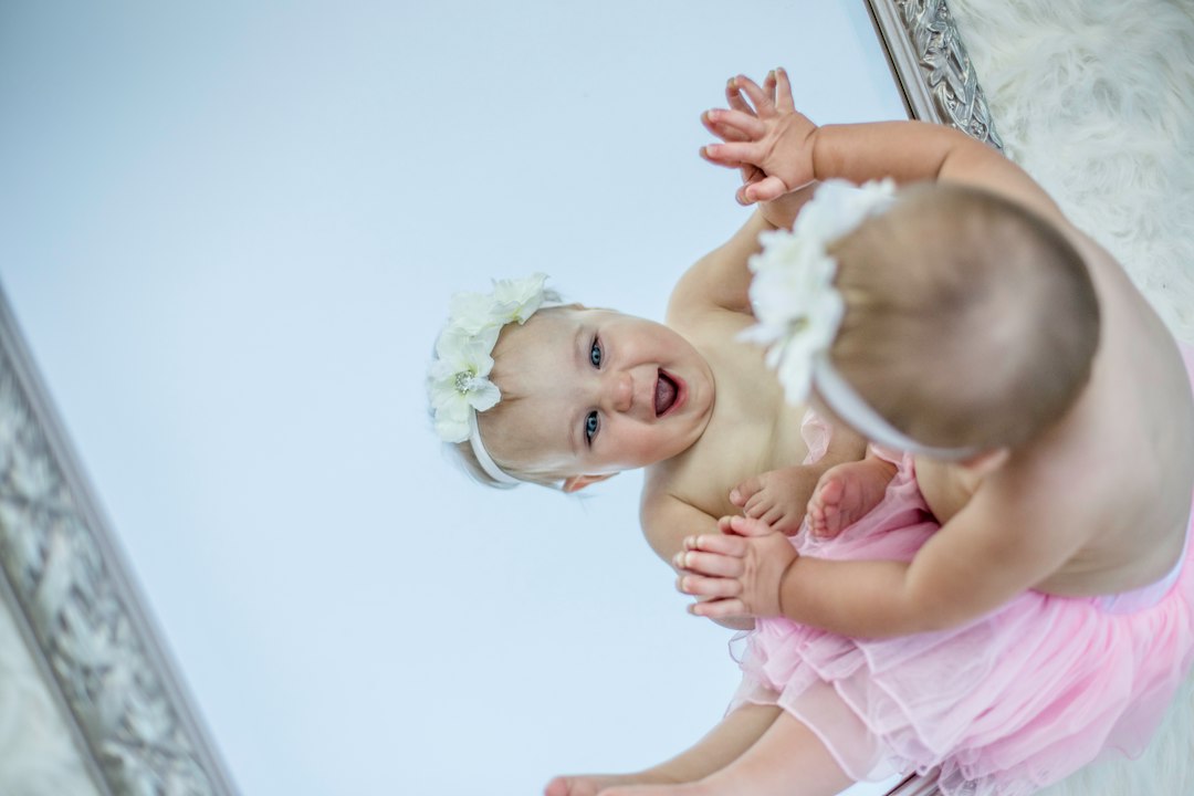 estimulación del lenguaje infantil - Un niño pequeño sonríe frente al espejo.